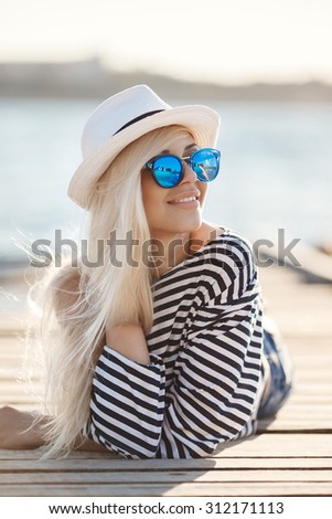 beautiful young pretty blonde woman in blue sunglasses and white summer hat by the sea. woman portrait. woman outdoor. sea style, beach and water. beauty portrait