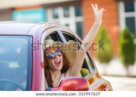 happy young woman in car driving on the road. Summer car travel freedom woman with arms raised up cheerful and happy. Summer road trip traveler concept.
