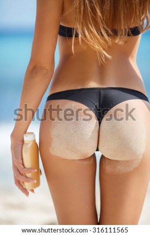 Sexy sandy woman buttocks on tropical beach background near ocean. close up outdoor shot of young woman in white bikini, sunbathing at sea shore. Black bikini on ocean background