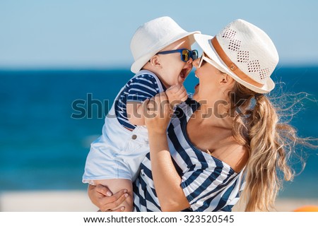Happy family relaxing by the sea. Happy family resting at beach in summer. mother with baby boy resting on the beach. Young mother and her adorable little daughter on beach vacation