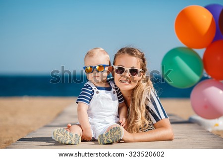 Happy family relaxing by the sea. Happy family resting at beach in summer. mother with baby boy resting on the beach. Young mother and her adorable little daughter on beach vacation