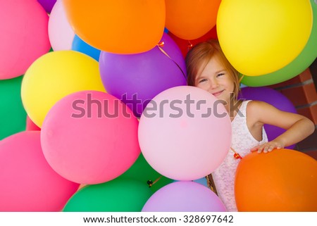 Little girl playing with balloons. Portrait of little girl playing with air balloons. Happy little girl holding colorful balloons.Smiling kid. happiness
