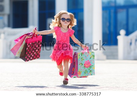 cute little girl on shopping. portrait of a kid with shopping bags. child in dress, sunglasses and shoes near shopping mall having fun. shopping. girl.