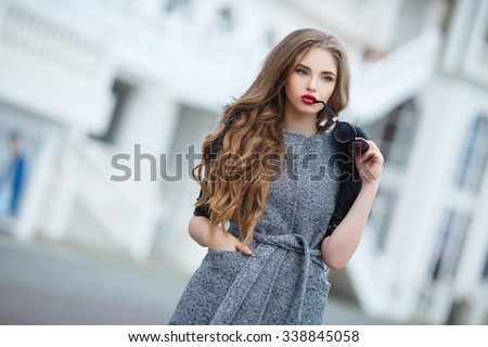 fashion outdoor photo of beautiful lady with dark hair wearing elegant coat,leather gloves and felt hat,posing in autumn park. Beautiful fashionable woman standing on the city street.