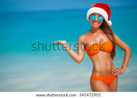 Young woman in santa hat on tropical beach. Christmas vacation. Christmas beach vacation travel woman wearing Santa hat and bikini enjoying christmas on tropical beach. woman in santa hat and bikini