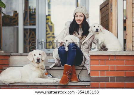 young beautiful woman in warm clothes with white labrador retrievers. dogs and woman. outdoor portrait. Pets and girl. Beautiful woman playing with her dog. Outdoor portrait. series