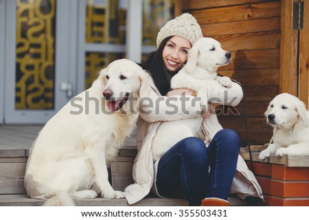 young beautiful woman in warm clothes with white labrador retrievers. dogs and woman. outdoor portrait. Pets and girl. Beautiful woman playing with her dogs, Puppy