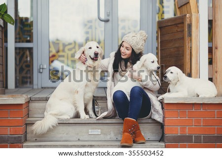 young beautiful woman in warm clothes with white labrador retrievers. dogs and woman. outdoor portrait. Pets and girl. Beautiful woman playing with her dogs, Puppy