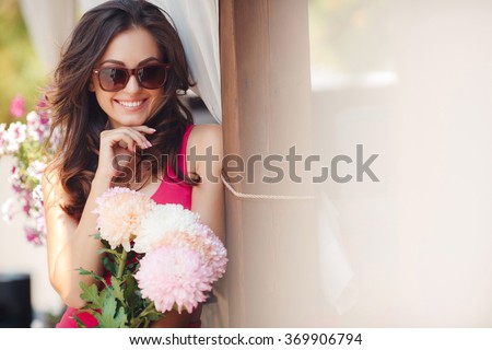 Happy woman holding flowers. woman with flowers walking in the city street. Closeup portrait of cute young girl with bunch of flowers smiling outdoors. Young woman with flowers