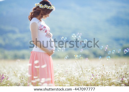 Outdoor portrait of unrecognizable young pregnant woman in the field. beautiful pregnant woman in wreath relaxing in the summer nature meadow. pregnant woman relaxing in flowers