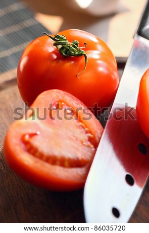 Choppes tomatoes with knife on wooden kitchen cutting board