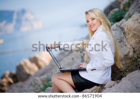 portrait of a beautiful woman near the sea with a laptop computer