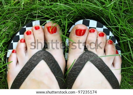 Beautiful female feet with pedicure relaxing on the grass in the park