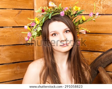 Naked nude girl with flower wreath on long thick hair on wood background as symbol of seduction, sex, youth, adolescence, beauty, summer, spring, freshness, fitness, rural country village life, sport