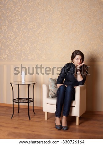Offend woman with sad face sitting in armchair after quarrel on beige background