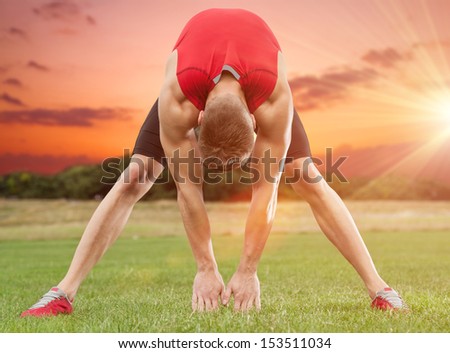 Muscular man stretching out in beautiful scenery