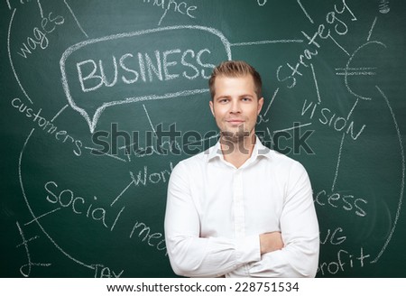 Young business man standing in front of a blackboard with a business plan