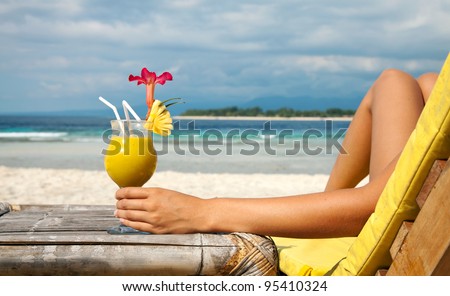 Woman holding a fruit cocktail on a tropical beach