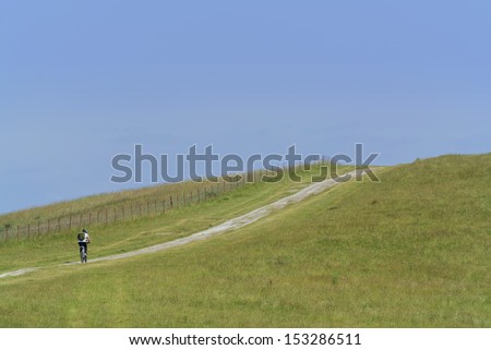 young man cycling up a hill in the south downs national park, sussex, uk