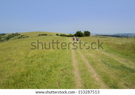 view from the south downs way footpath, sussex, england uk - fit senior couple walking on footpath