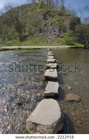 stepping stones across river wooded landscape on other side