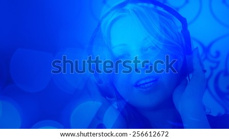 Young pretty woman listening music blue light background