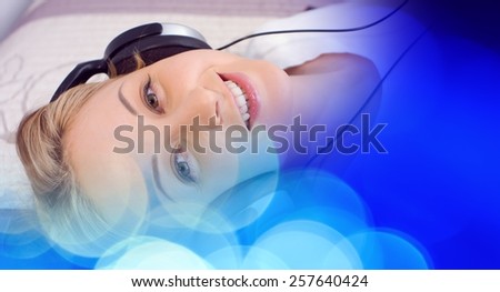 Pretty young woman in headphones listening music, blue lights background