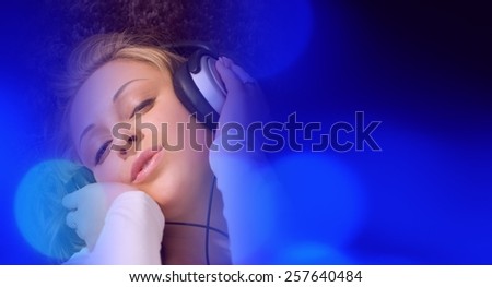 Young woman listening to the music, blue lights background