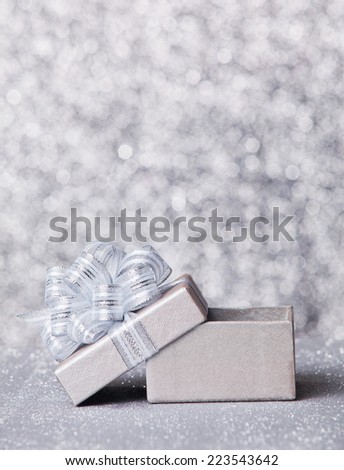 gift box with silver ribbon, glittery silver background
