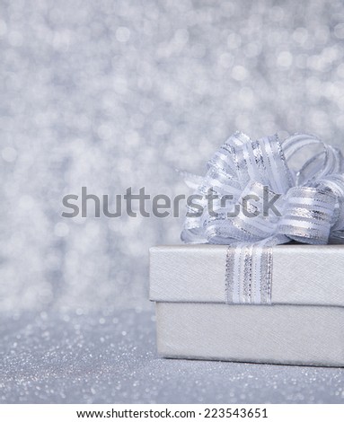 gift box with silver ribbon, glittery silver background