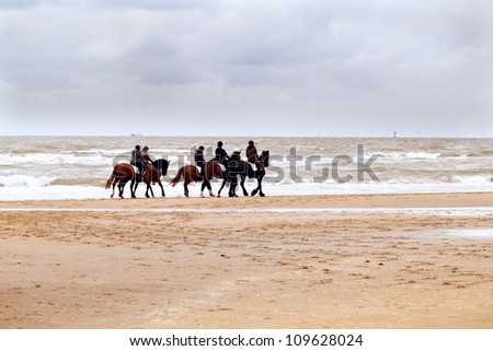 few riders on horses on the beach close to North sea