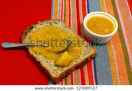 piece of bread and jam of apricot on the colorful napkin