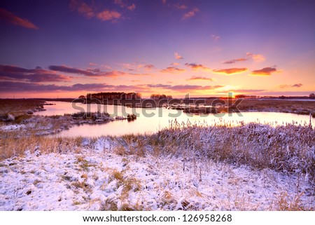 dramatic sunrise over frozen lake in winter