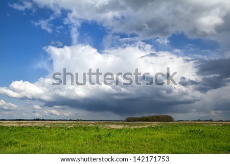 dramatic storm clouds over green plain meadow