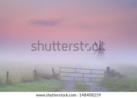 Dutch windmill in dense fog at sunrise, Groningen, Netherlands