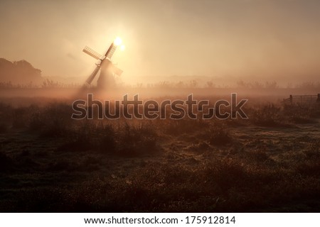 sunshine behind windmill in misty morning, Holland