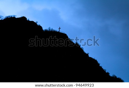 black silhouette of the cross on the hill over dark blue sky