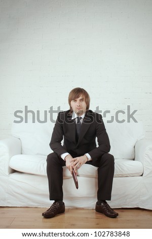 businessman in white room - man in suit sitting on the white couch
