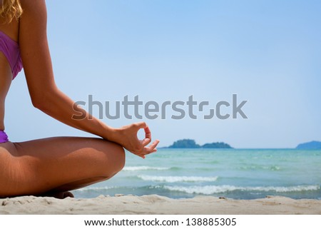 yoga background, woman in lotus position meditating on the beach