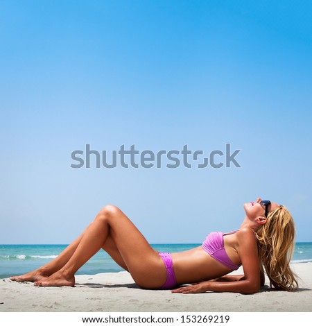 young blond woman with perfect shapes enjoying the sun on the beach