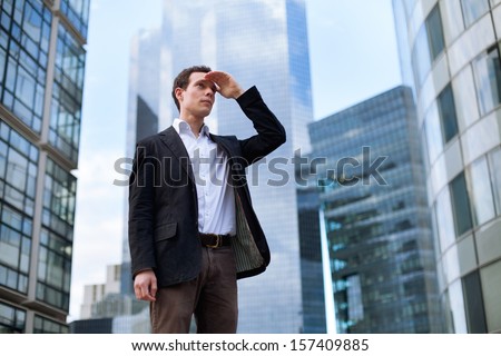 young business man looking forward on skyscrapers background