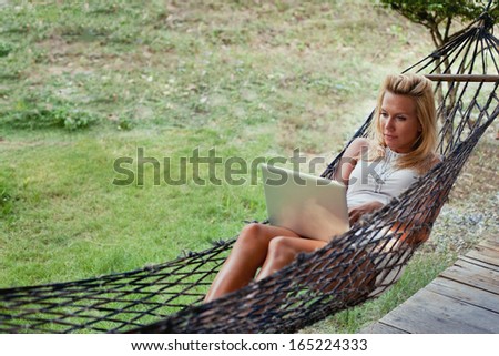 young blond woman with laptop in hammock