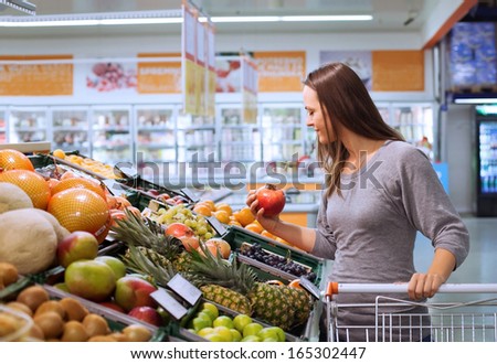 young woman in supermarket choosing fruits