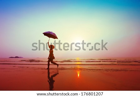 happy woman jumping with umbrella on the beach