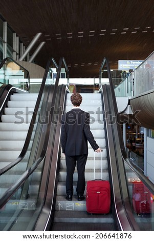 business travel, man with luggage on escalator in airport