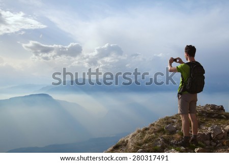 hiker taking photo of beautiful mountain landscape with mobile phone