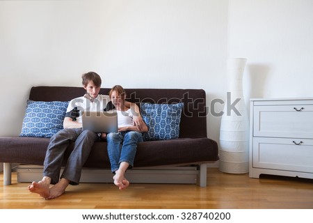young family using laptop at home, couple on the couch with computer