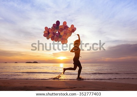 happiness and inspiration concept, psychology of happy people, young woman running with multicolored balloons on the beach