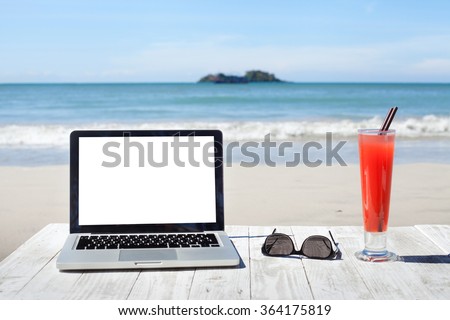 office on the beach, laptop with empty screen, sunglasses and tropical cocktail