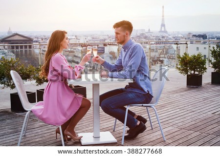 couple drinking champagne in luxury rooftop restaurant in Paris with panoramic view of Eiffel Tower